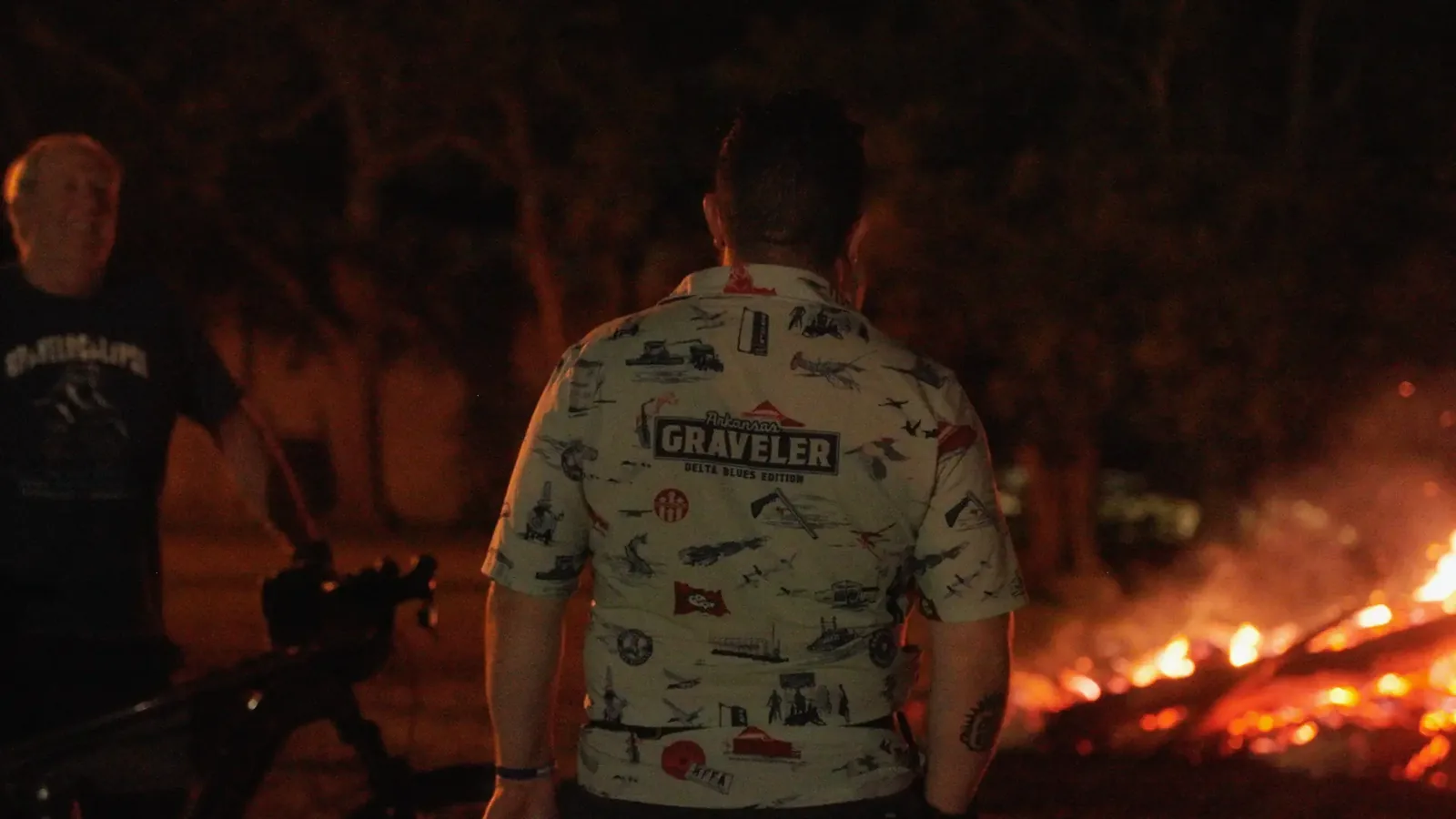 A rider in the Arkansas Graveler Delta Blues Edition camp shirt standing by the fire on the last night in Arkansas City.